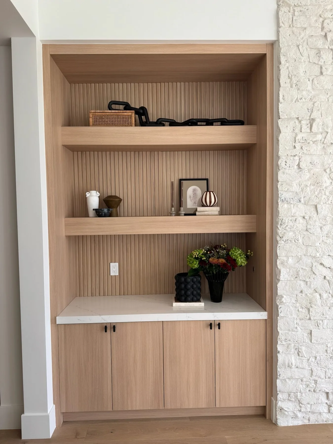 Built-in shelving niche with fluted wood detail