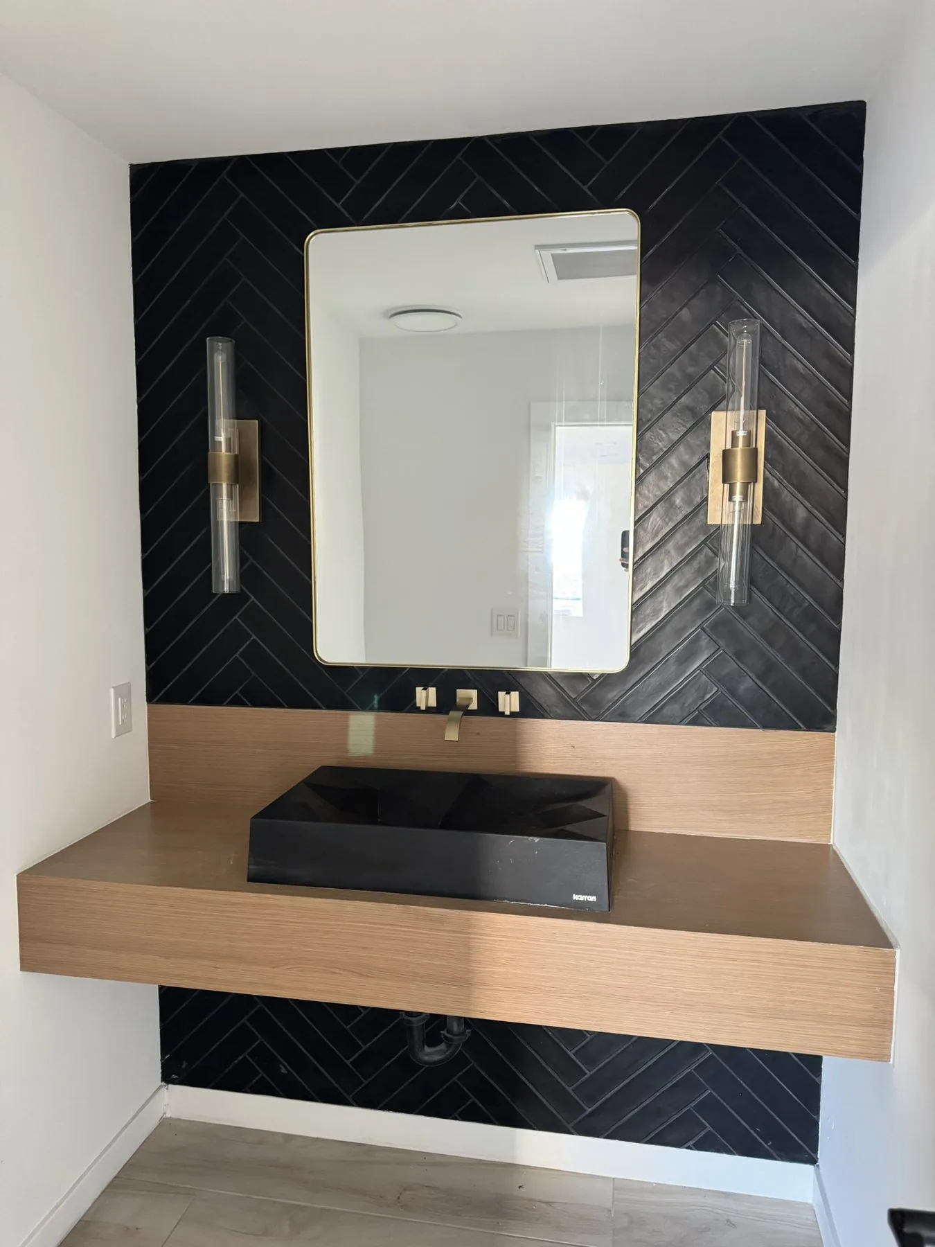 Navy herringbone tile accent wall with a floating wood vanity